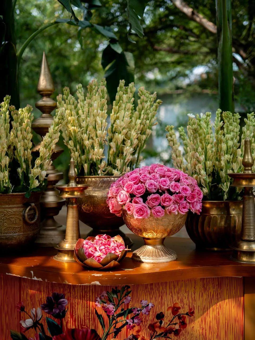 Pink rose and tuberose arrangement in antique brass urns at a sundowner wedding
