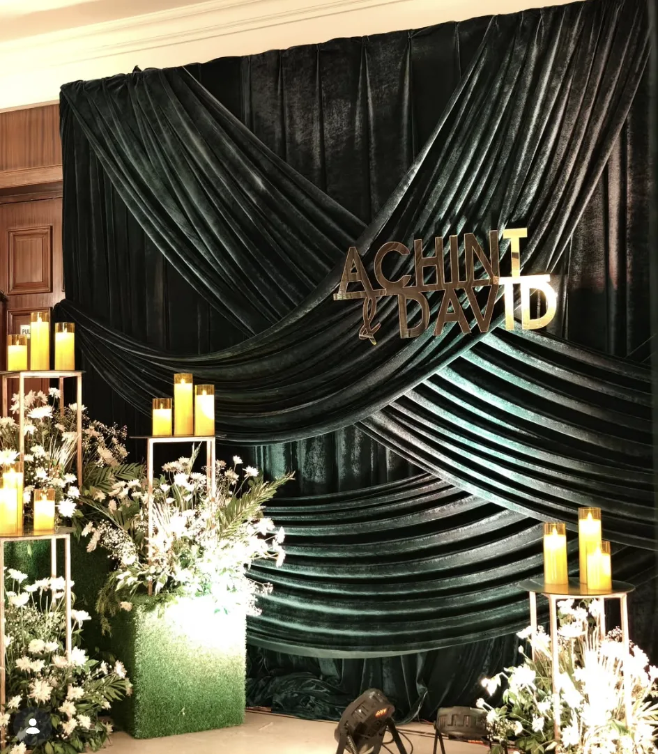 Draped velvet wedding backdrop with Achint and David's names, styled with candles and florals, in Kasauli