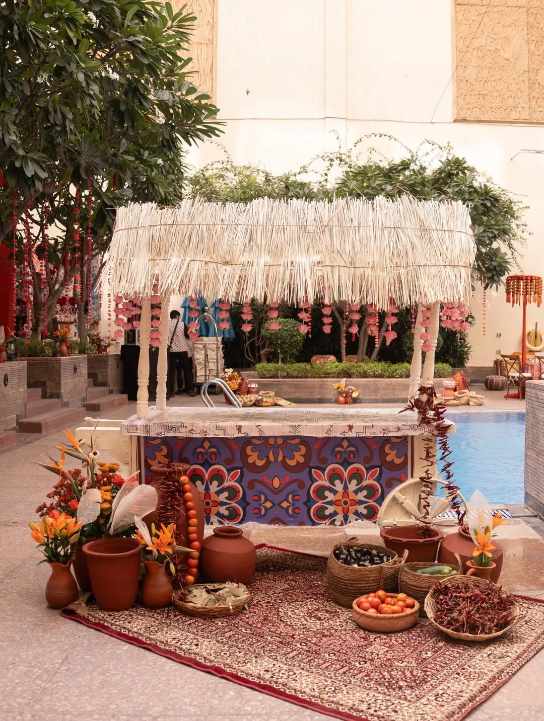 Rustic thatched cart styled with spices and florals beside the pool at a Rajasthan mehendi ceremony